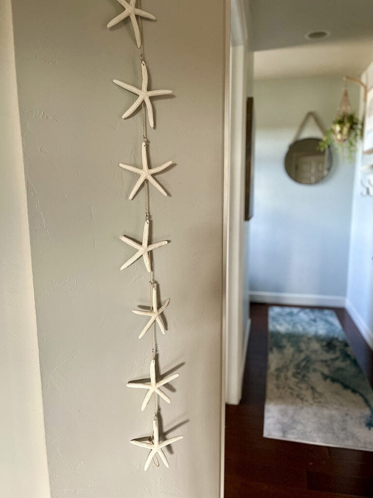 A vertical starfish garland hanging on a wall, inspired by a family vacation to Anna Maria Island, adding a coastal touch to the decor.