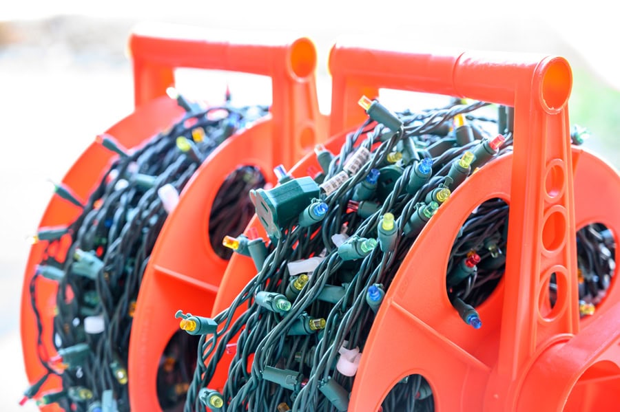 Christmas lights neatly wound onto orange reels for efficient Christmas decoration storage.