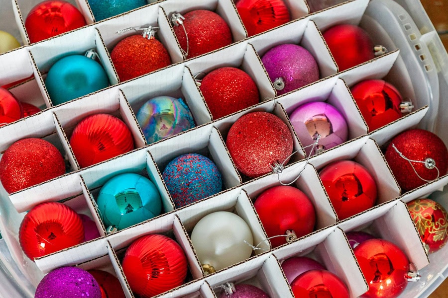 Plastic bin filled with neatly organized Christmas ornaments in individual compartments.