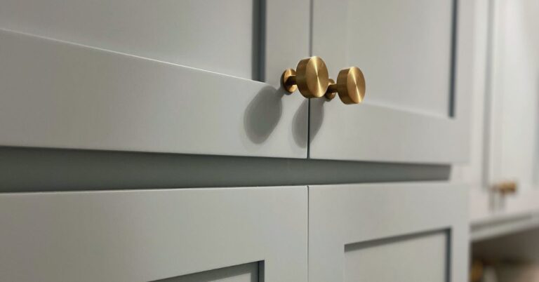 Close-up of Niebla Azul blue cabinet paint with brushed gold knobs, showcasing the perfect coastal blue cabinetry color.