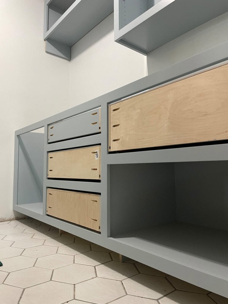 Custom-built shaker-style cabinets in soft blue, partially installed during a laundry room makeover.