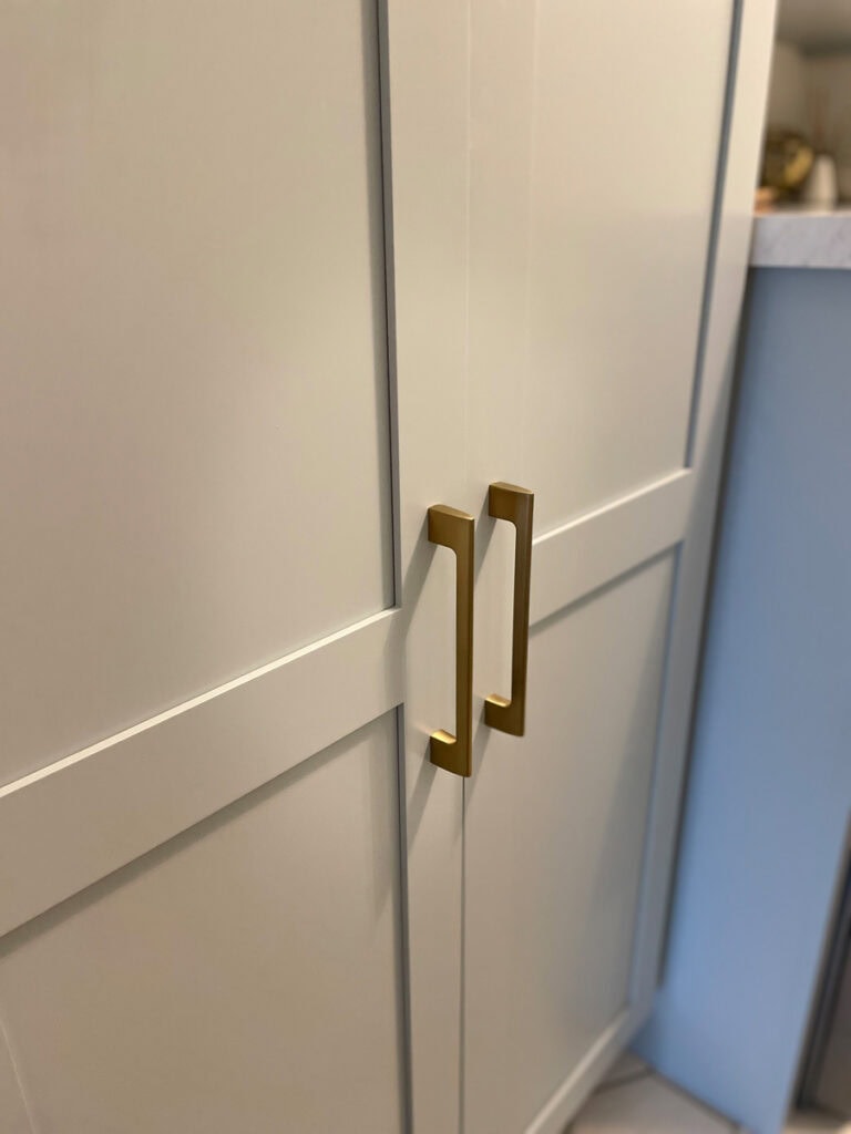 Tall storage cabinet featuring long Golden Champagne handles. The elongated hardware adds a sophisticated, modern touch while keeping the laundry room and pantry makeover practical and stylish.