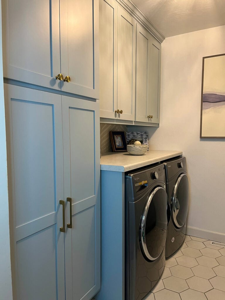 Laundry room makeover with blue shaker cabinets, built-in washer and dryer, and added countertop for folding and storage.