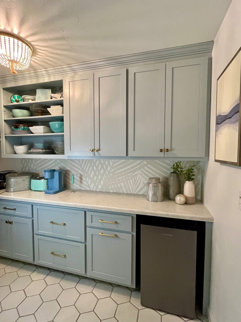 Pantry makeover with marble-look laminate countertops, soft blue shaker cabinets, and gold hardware. Open shelving with dishes and decorative pieces.