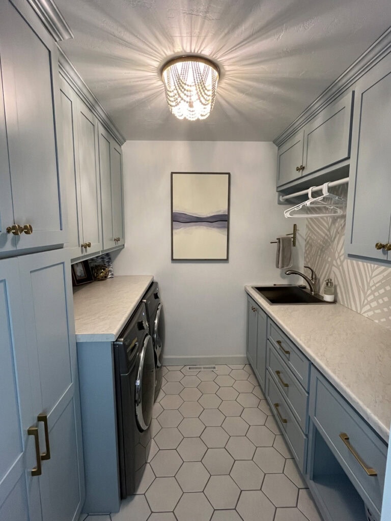 Laundry room makeover with blue cabinets, hex tile flooring, and minimalist wall art for a clean, coastal-inspired space.