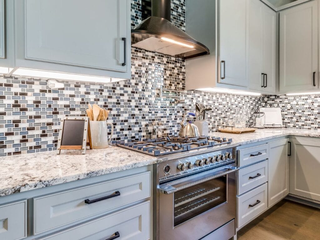 Light painted cabinets paired with a bold, colorful mosaic backsplash.