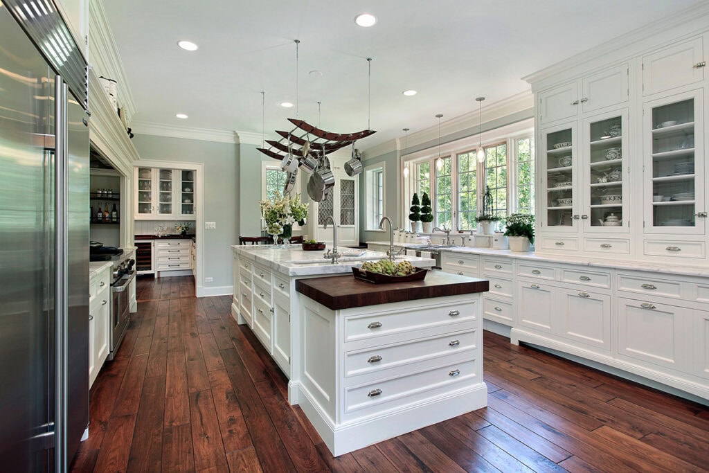 White perimeter cabinetry with a rich wood island and warm floors.