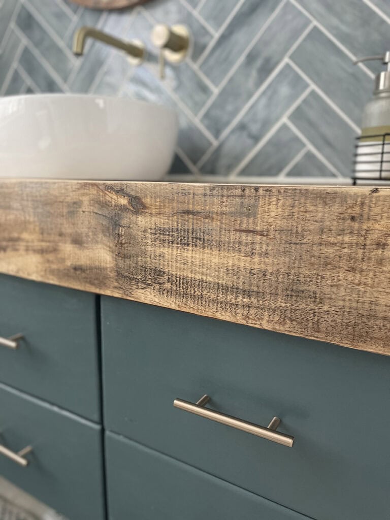 Painted powder room vanity with stained wood countertop in a small coastal space.