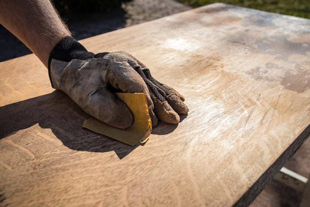 Close-up of sanding stained cabinetry during a DIY cabinet refinish project.