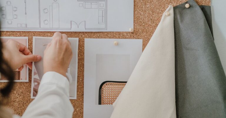 photograph showcases a designer working on a mood board for a coastal-inspired space, pinning images and fabric swatches to a corkboard.