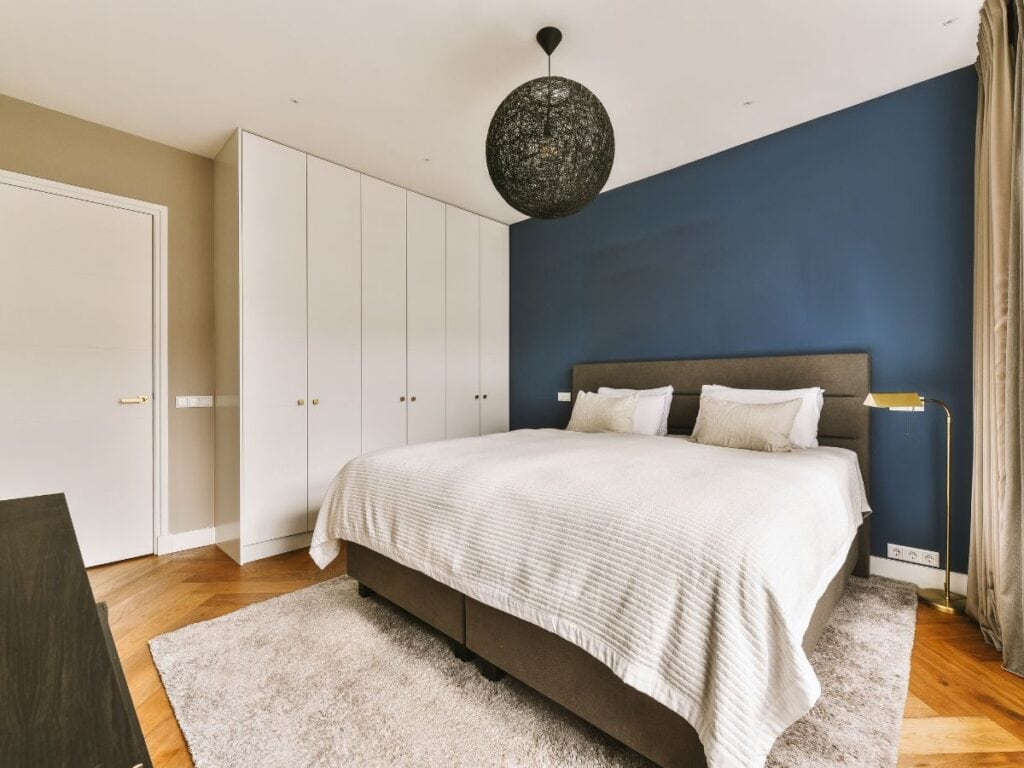 Bedroom with bold blue accent wall and warm-toned floors
