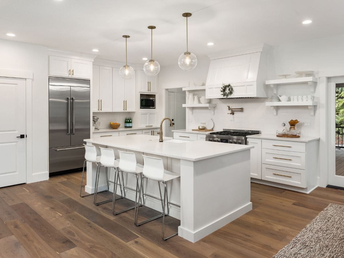 White coastal kitchen with warm wood floors, brass hardware, and natural light
Caption: Light and finishes change everything—especially with whites.