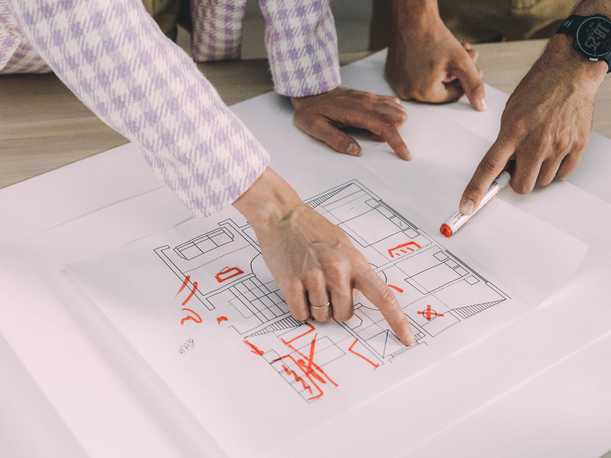 Hands pointing to a marked-up renovation floor plan, reviewing layout adjustments before finalizing furniture and renovation decisions.