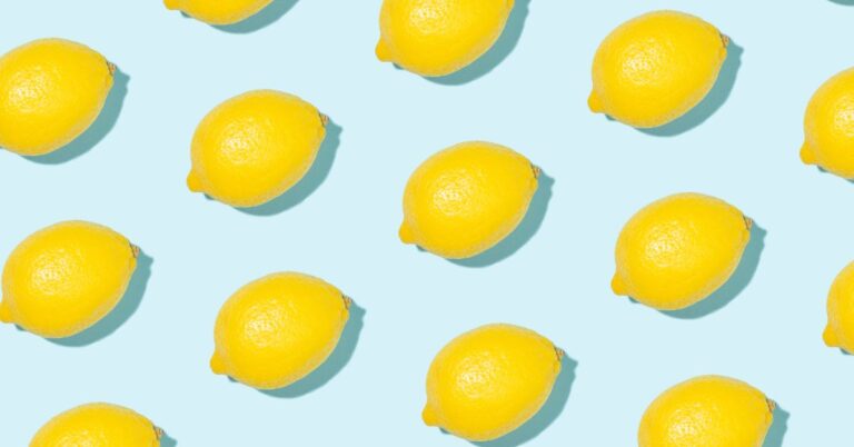Pattern of bright yellow lemons scattered across a light coastal blue background, symbolizing cheerful lemon yellow home decor inspiration.