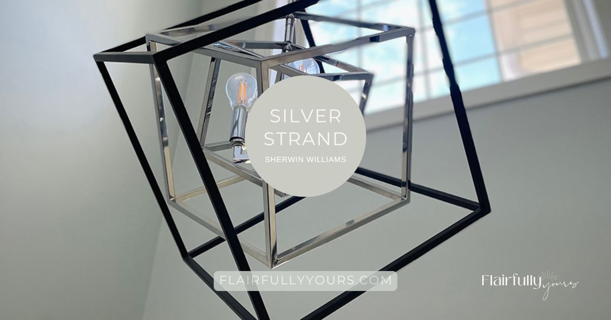 Modern black and silver geometric light fixture against walls painted in SW Silver Strand, a coastal chameleon paint color from Sherwin Williams.