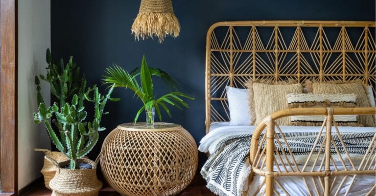 Coastal bedroom with rattan headboard and woven accents adding natural textures against navy walls.