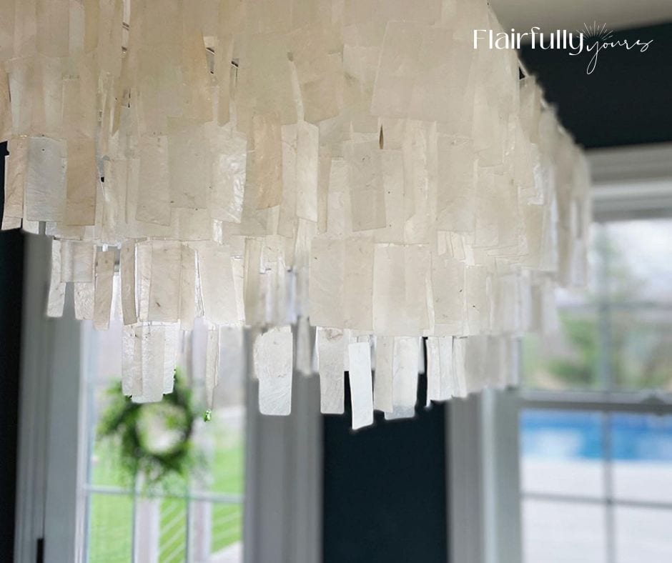 Capiz coastal chandelier with layered shell panels reflecting natural light in a dining space.