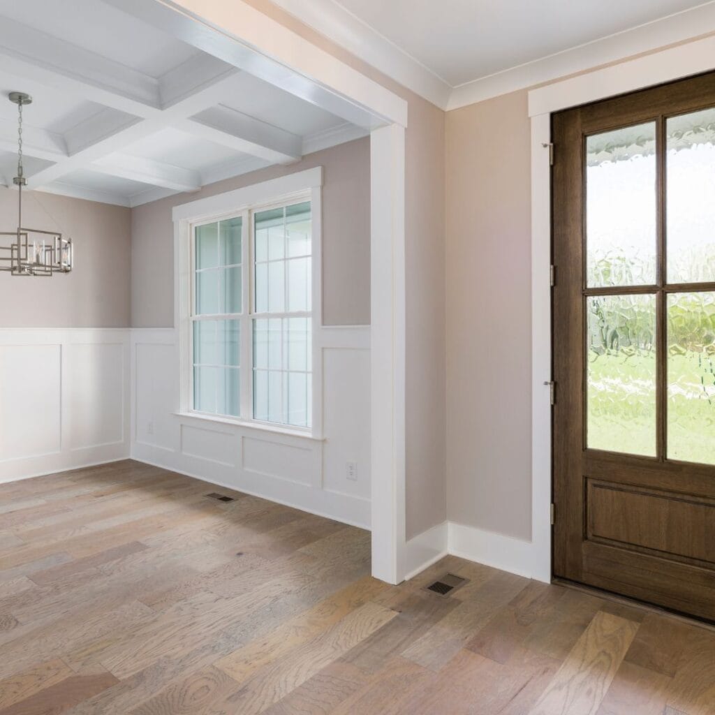 Entryway with stained wood door framed by white trim and neutral walls, showing how wood doors add warmth while white trim keeps the look timeless.