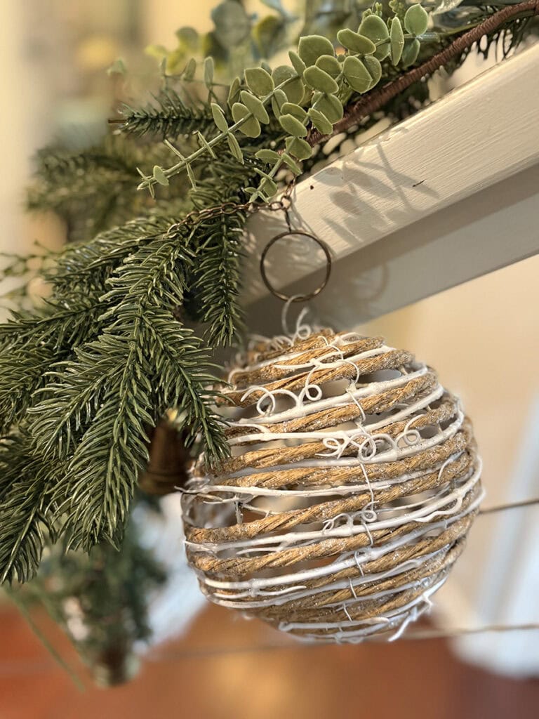 Coastal staircase garland with large rope-wrapped ornament and greenery.