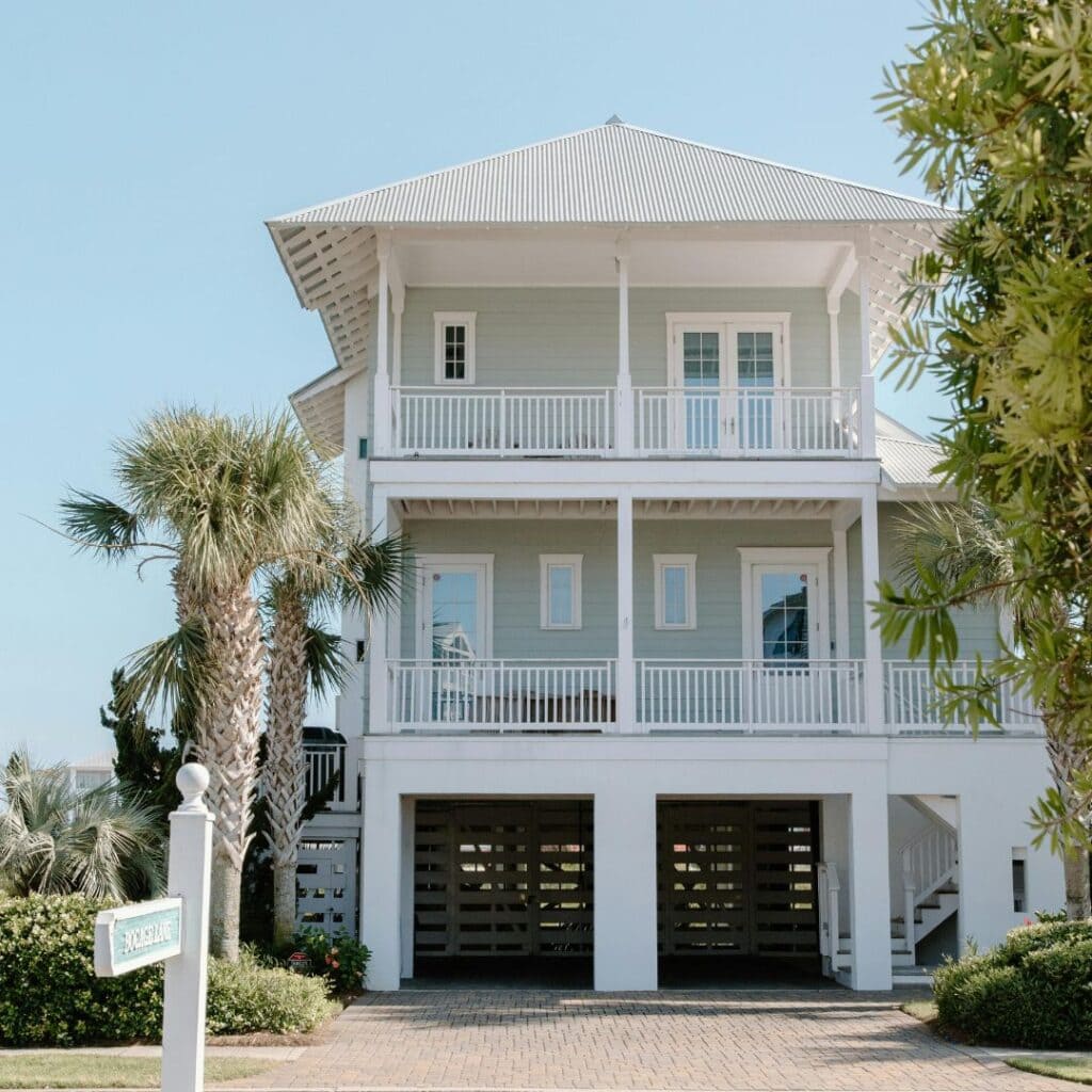 Soft blue beach house exterior with white trim, palm trees, and double porches showing calm coastal exterior paint colors.