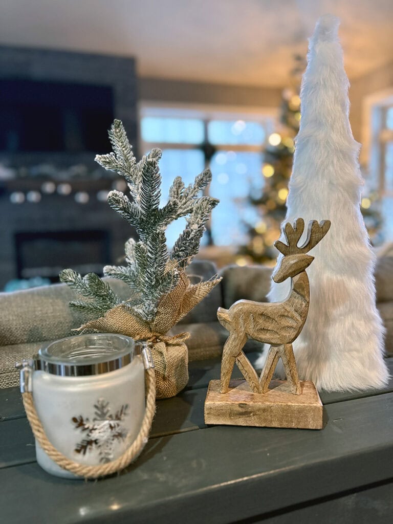 coastal Christmas console display with wooden reindeer, frosted mini tree in burlap, white faux-fur tabletop tree, and snowflake candle with rope handle