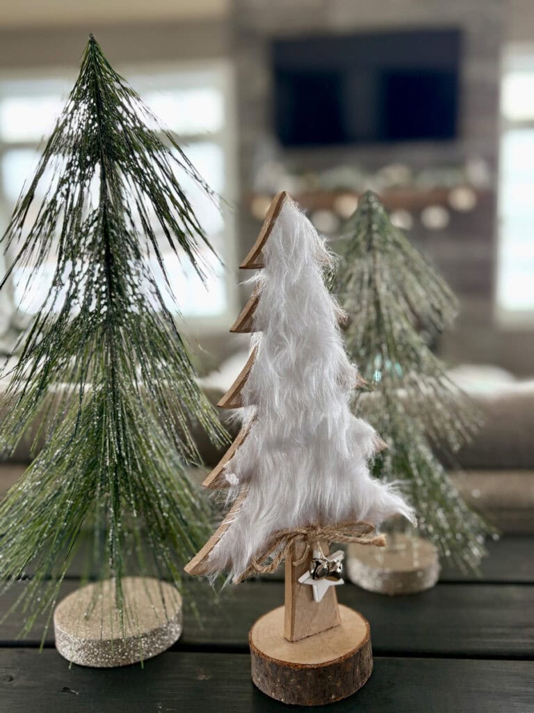 tall coastal Christmas tabletop trees used as height makers on a console table to create a festive layered holiday display