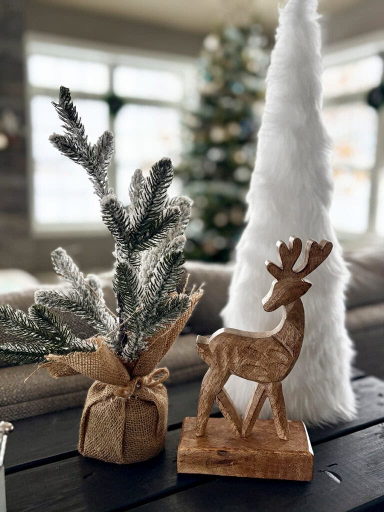 coastal Christmas console table with wooden reindeer figurine, frosted greenery, and soft white tree showing how to add personality with holiday character pieces