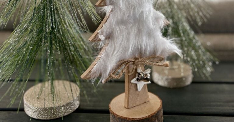 Coastal Christmas table décor close-up featuring a white faux-fur tree and sparkly greenery on a dark wood console.