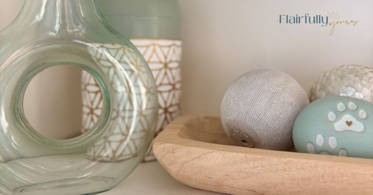 Shelf decor styled with soft aqua glass, warm wood bowl, and neutral accents creating a calm, cohesive color palette.