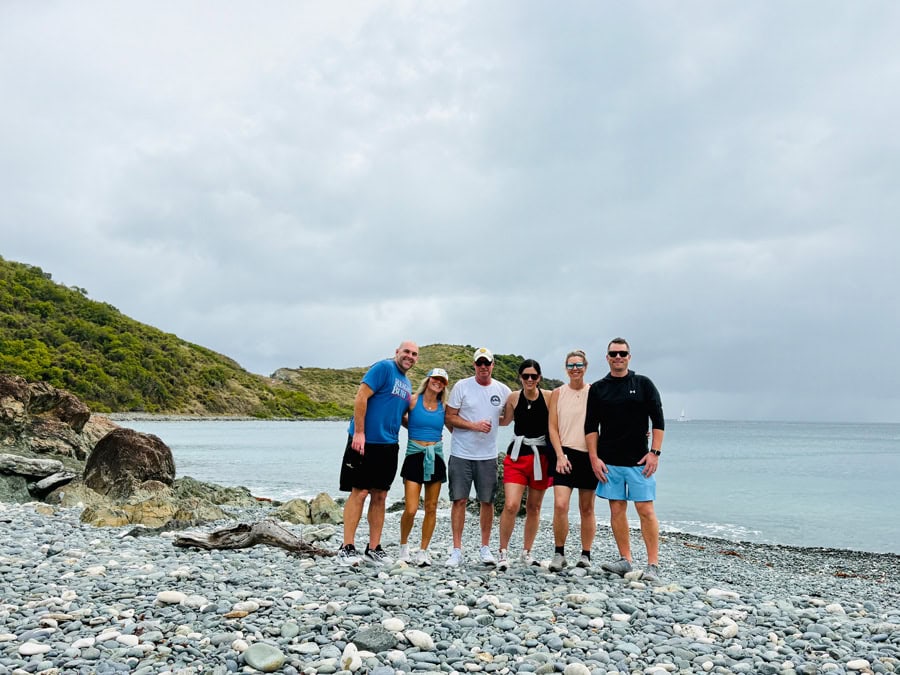 Group of friends at Blue Cobblestone Beach, St. John, surrounded by blue-tinted stones along the shore.