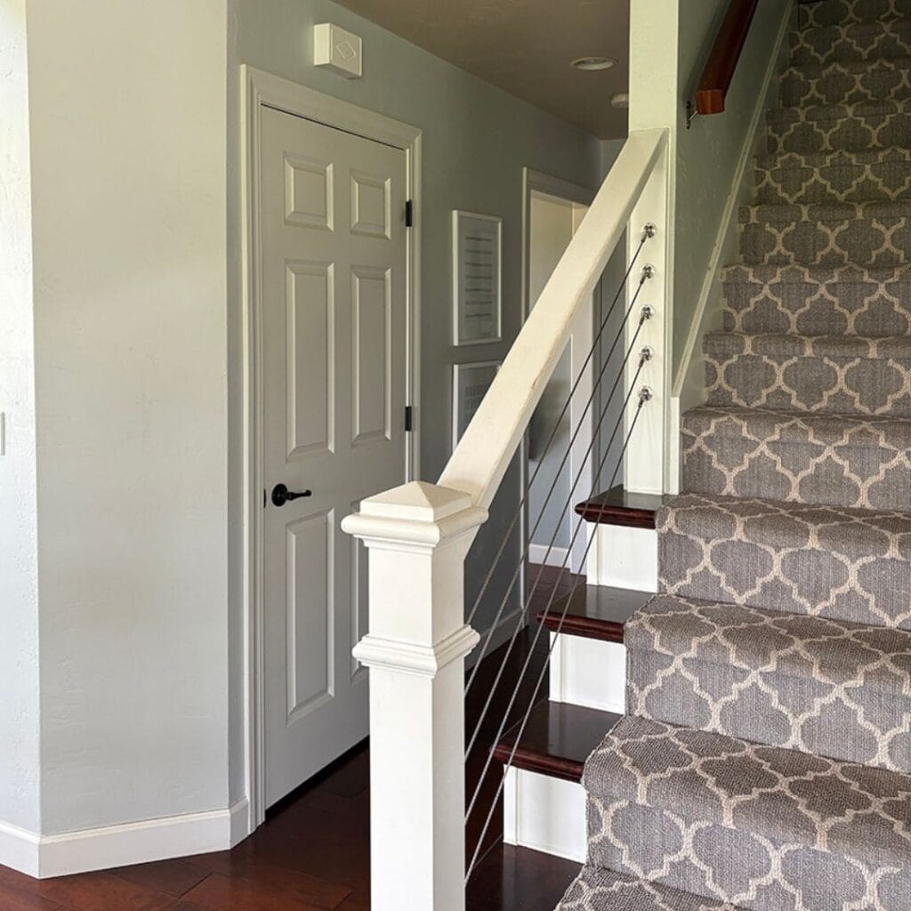 Staircase with white trim and soft gray walls showing how white trim enhances space by reflecting light.