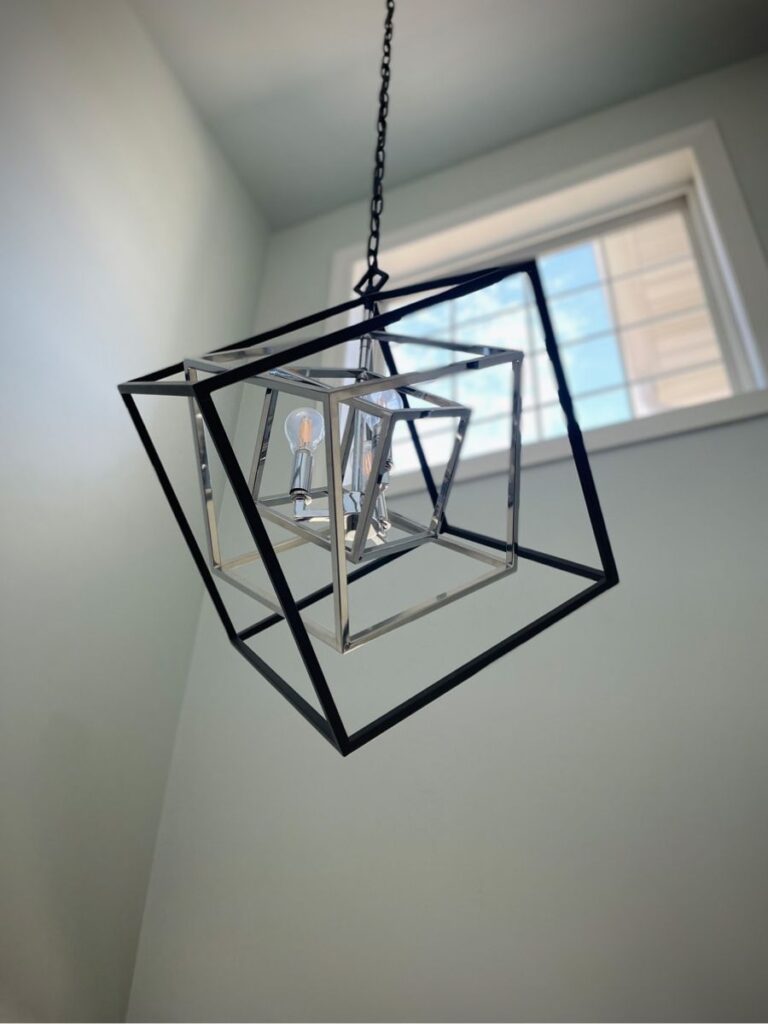 Modern geometric black-and-silver light fixture in the entryway, brightening the space with a minimalist design.