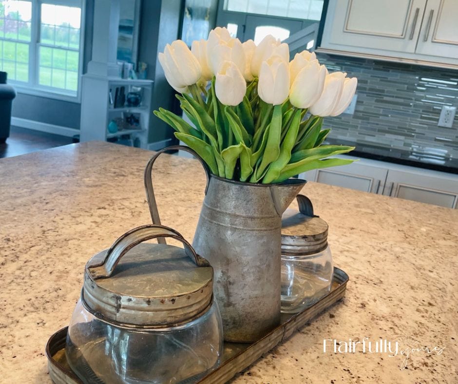 Faux white tulips in a galvanized pitcher on a kitchen island, adding a fresh spring touch to your home decor.