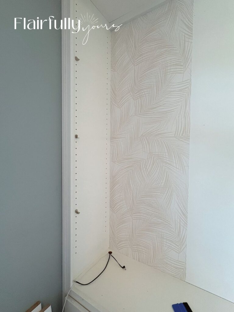 Peel-and-stick palm wallpaper being applied to a shelf with smooth, steady motion to avoid air bubbles.