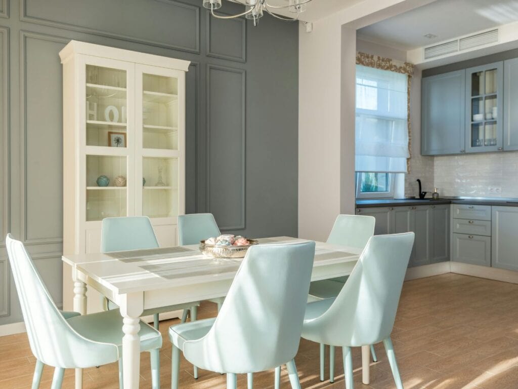 Dining room showing pale blue-green chairs, a white table, and gray cabinets illustrating light, medium, and dark shades for how to decorate using tonal layering.