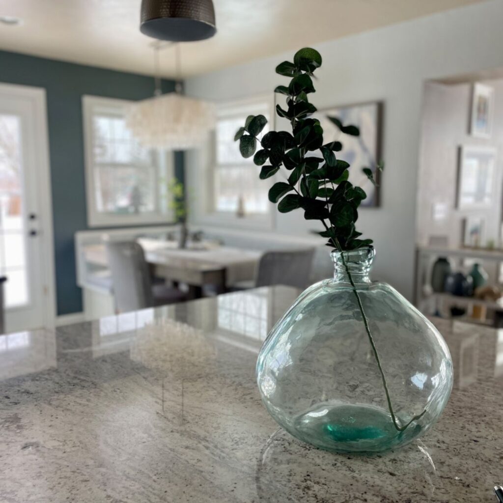 Simple coastal and lake house decor featuring a large blue glass vase with greenery, demonstrating how fewer, thoughtfully chosen pieces create a calm, cohesive home.