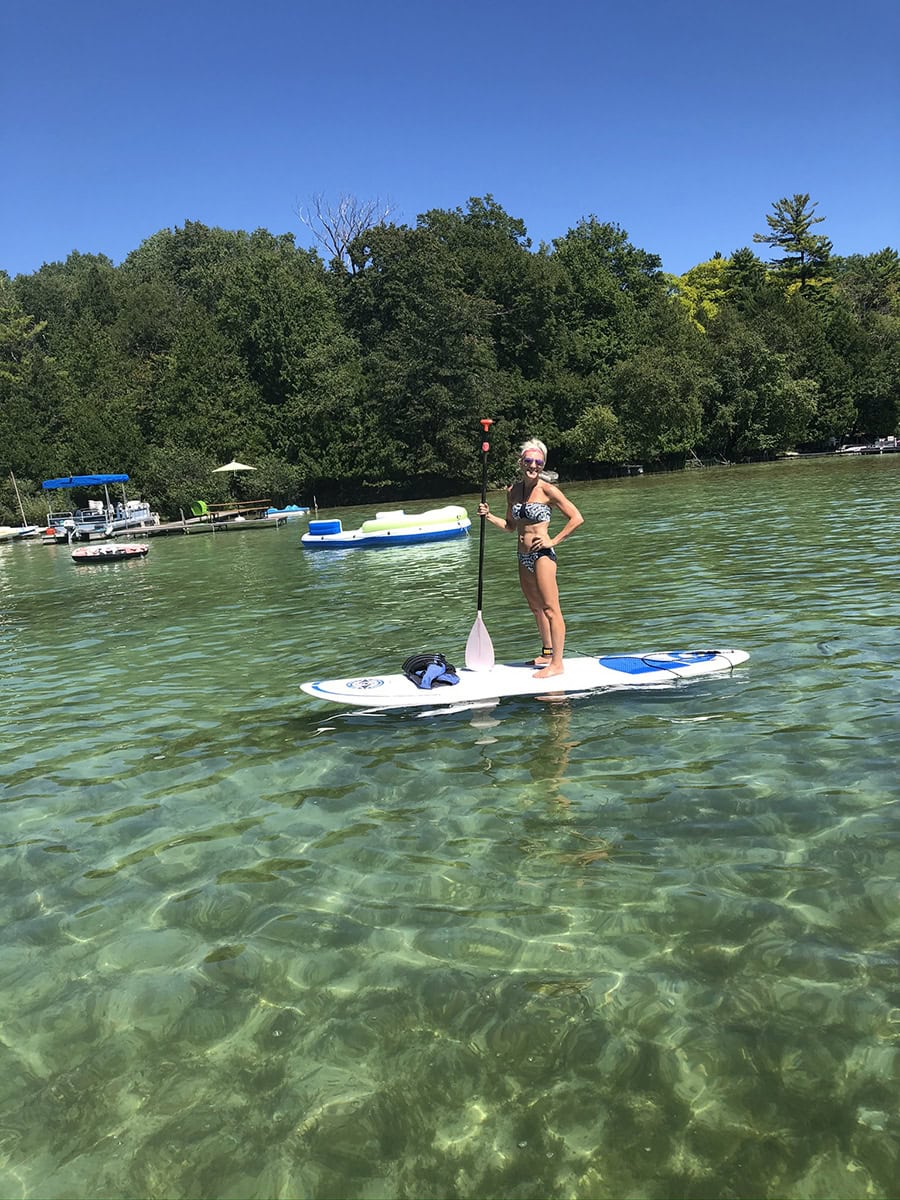 Wendy paddleboarding on a clear Wisconsin lake on a sunny summer day.