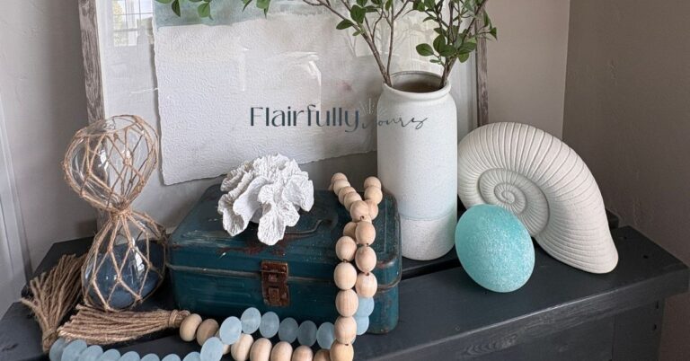 Coastal console table styled with sea glass beads, white coral, nautilus shell, aqua glass ball and rope-wrapped hourglass