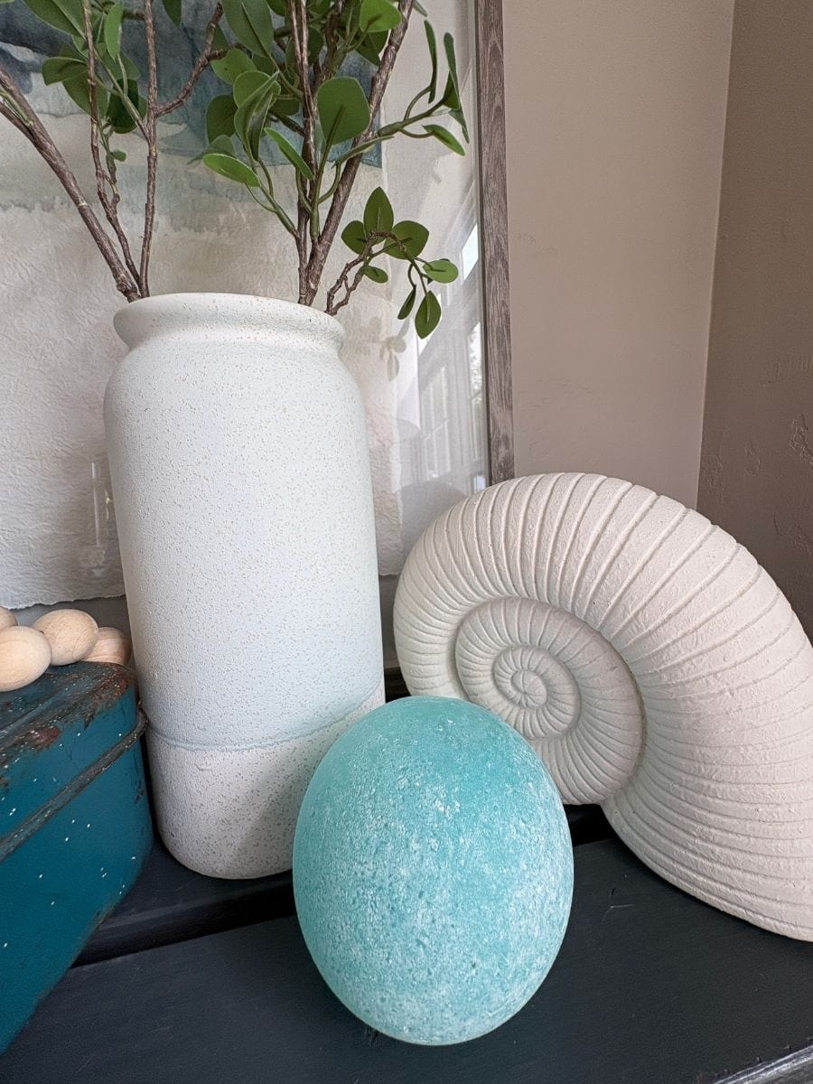 White nautilus shell and aqua glass ball adding sculptural shape to coastal console table decor