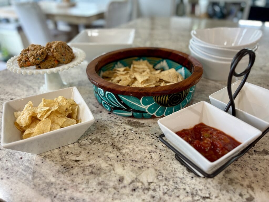 Chips, salsa and cookies served in white dishes with a colorful statement bowl for casual home entertaining.