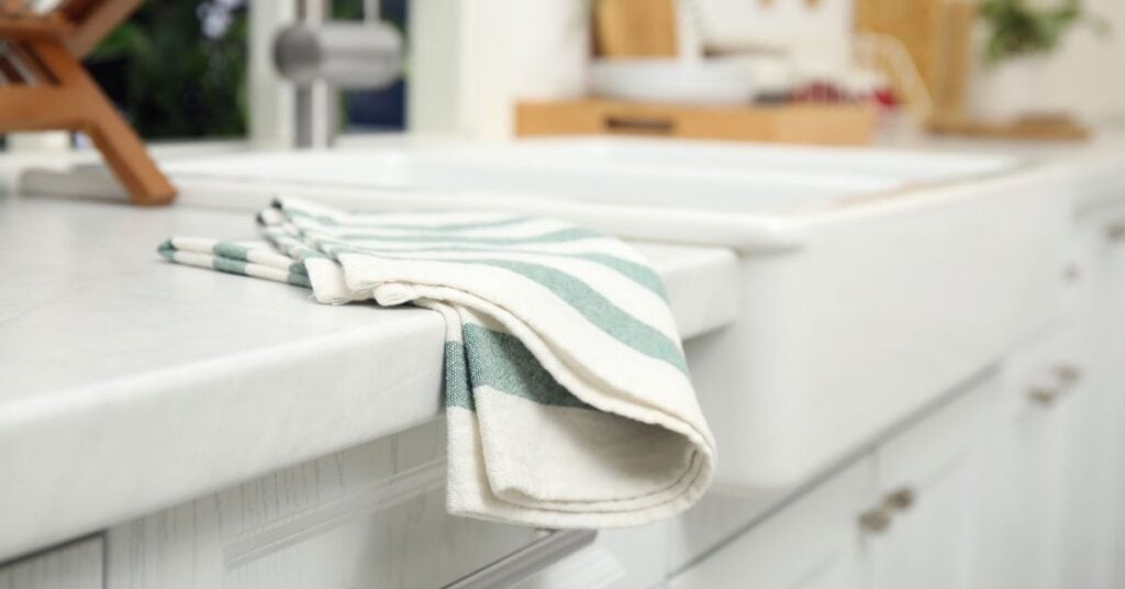 Aqua and white striped kitchen towel draped over a white kitchen counter.
