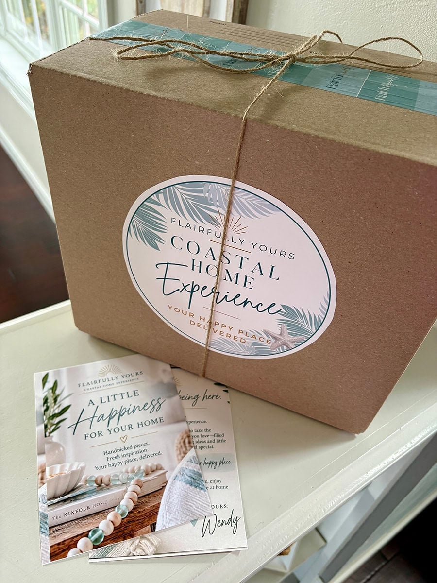 Flairfully Yours Coastal Home Experience subscription box wrapped with branded aqua tape and twine, displayed with welcome cards featuring a personal message from Wendy.